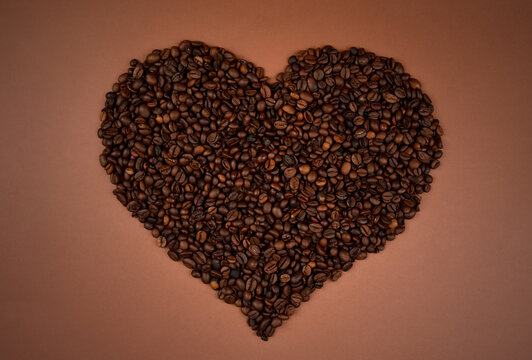 Roasted coffee beans in heart shaped stock images. Heart shaped coffee beans top view isolated on a brown background stock photo