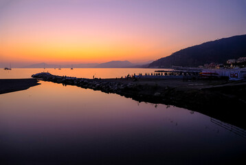 Beautiful pink sunset in sea across boats, mountains on the horizon. Natural background. vacation at sea. Sestri Levante, Liguria, Italy