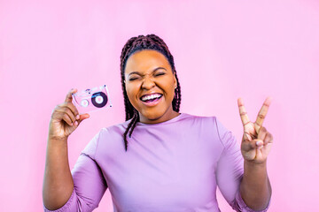 hipster lady with cool dreadlocks pigtails showing audio cassette old fashion school in pink studio background
