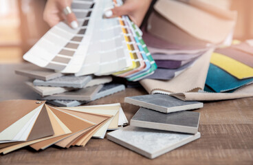 Interior designer decorator choosing wall paint color to match with chooses fabrics for furniture...