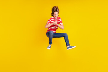 Fototapeta na wymiar Full length body size view of attractive cheerful guy jumping having fun good mood isolated over shine yellow color background