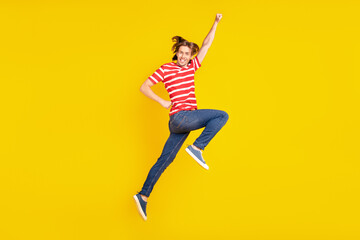 Photo of sweet charming young guy dressed red t-shirt jumping high smiling isolated yellow color background
