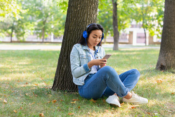 Portrait of an Asian woman in headphones with smartphone. She smiles and listens to her favorite music.