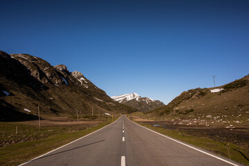 Carretera recta con montañas nevadas de fondo.