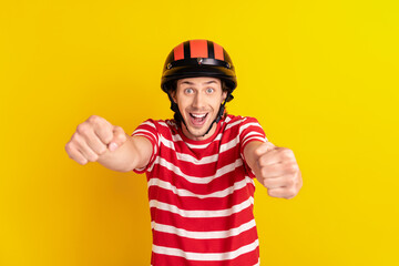 Portrait of attractive cheerful childish guy riding invisible car having fun isolated over bright yellow color background