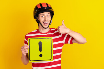 Photo of cute funny guy dressed red t-shirt safety hat showing thumb up holding beware banner isolated yellow color background