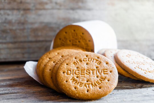 Digestive biscuits scattered on a rustic wooden background. On the cookies you can read -Biscuits digestive wheatmeal- 