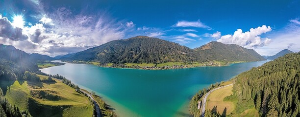 Fototapeta premium Drone panorama over turquoise lake Weissensee in Austrian province of Carinthia during daytime