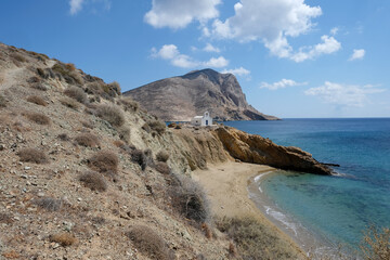 Fototapeta na wymiar Anafi island - sandy beach and the small church of Agioi Anargyroi, on the back Kalamos Rock monolith. Cyclades islands, Greece 