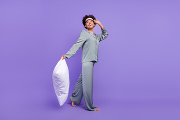 Photo of adorable funny woman grey sleepwear smiling holding pillow walking looking empty space isolated violet color background