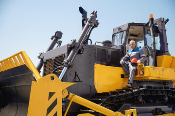 Industrial portrait of working man, excavator driver climbs into cab to perform work on...