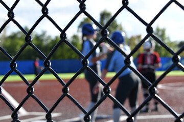 Chain Link Fence at a Softball Field with a Game Being Played