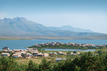 Fototapeta na wymiar View of a village located on peninsula at the lake with mountains background