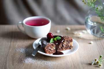 Still life with chocolate cake and cup of pink hibiscus tea