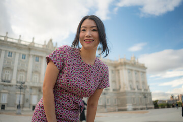 urban lifestyle outdoors portrait of young happy and beautiful Asian Japanese woman  in sweet Autumn dress enjoying Madrid city tour relaxed and smiling cheerful during palace visit