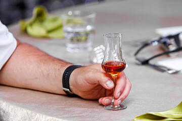 Man holding a glass of cognac at a banquet.