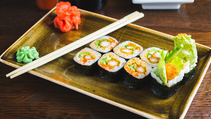 Traditional Japanese rolls with shrimps and vegetables on a plate with wooden chopsticks