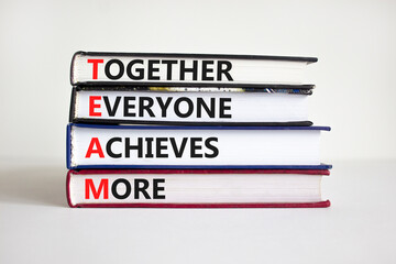 TEAM, together everyone achieves more symbol. Concept words 'TEAM, together everyone achieves more' on books. Beautiful white background, copy space. Business, motivational and TEAM concept.