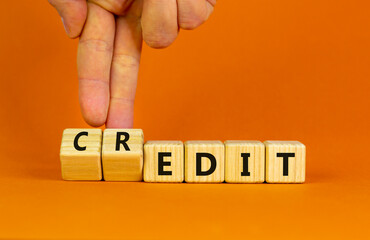 Credit to the edit symbol. Businessman turns wooden cubes and changes the word 'edit' to 'credit'. Beautiful orange background. Business, credit to the edit concept. Copy space.