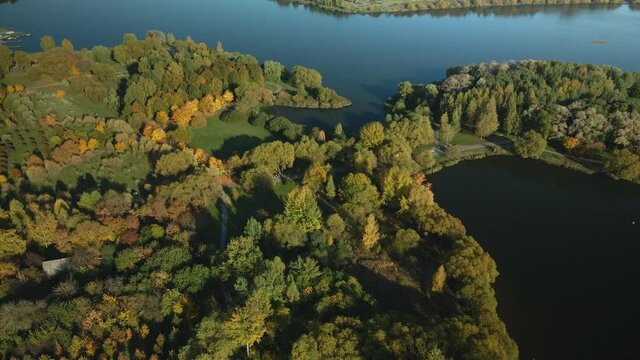 Flight over the autumn park. Park on the shore of a large lake. Trees with yellow autumn leaves are visible.  Aerial photography.