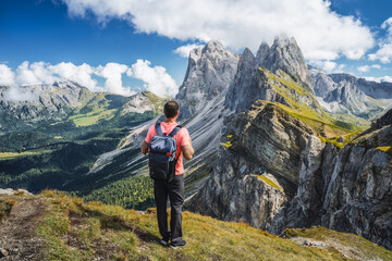 Fototapeta na wymiar A man with backpack enjoy landscape of Seceda peak in Dolomites Alps, Odle mountain range, South Tyrol, Italy, Europe. Travel vacation concept