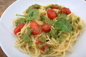 spaguetti pesto sauce with cherry tomatoes and basil