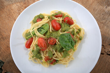 spaguetti pesto sauce with cherry tomatoes and basil