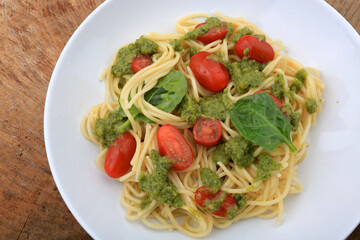 spaguetti pesto sauce with cherry tomatoes and basil