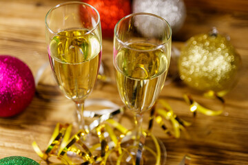 Two glasses of champagne and festive Christmas decorations on wooden table. Christmas and New Year celebration