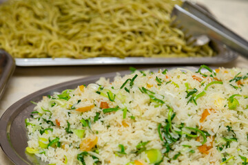 Pratos com arroz e macarrão em mesa de bufê para festa de aniversário.