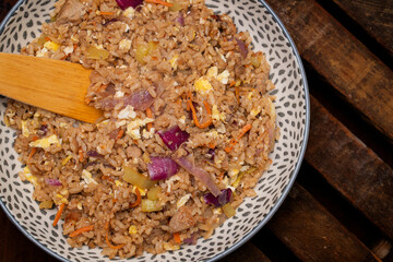 Pork fried rice in a serving bowl with a wooden spoon