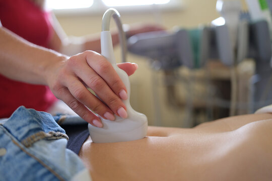 Ultrasound scanner in hands of doctor examines woman pelvis