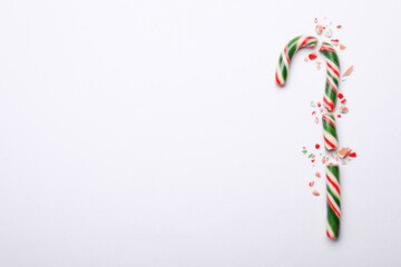 Broken sweet Christmas candy cane on white background, top view. Space for text