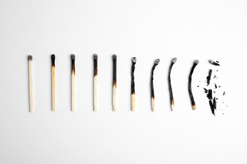 Different stages of burnt matches on white background, flat lay