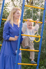 little boy with his mother  on playground on summer day