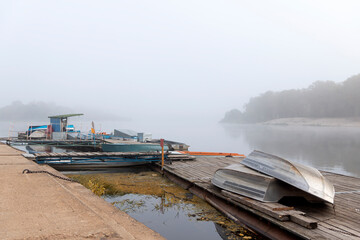 Fishing boats, small boats, moored to the pier in thick fog.