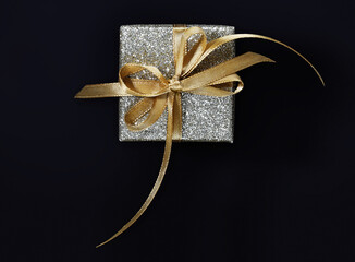 merry christmas gift silver box with golden ribbon bow, isolated on black background, top view and copy space template, layout useful for best wishes or black friday shopping concept
