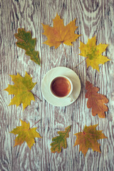 Fallen autumn leaves scattered around a cup of espresso on a wooden table, stylized