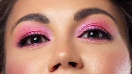 Beautiful macro of expressive brown eyes with fashionable pink smoky shadows, extremely long...