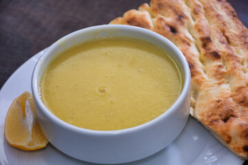 Traditional Turkish lentil soup served with a slice of lemon and tandoori bread near the plate