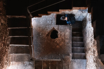 The young man descends into the darkness. Gloomy stone staircase leading down to the old tower....