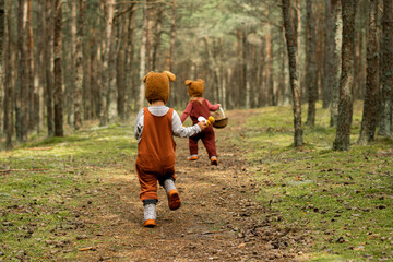 Toddler baby twins in bear bonnets playing and having fun in the woods - obrazy, fototapety, plakaty