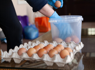 Hands in rubber gloves shift fresh chicken eggs..