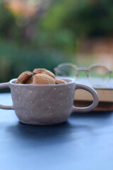 Bowl of cinnamon cookies, hardcover books and reaing glasses. Selective focus.