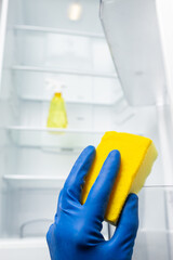 Hands cleaning refrigerator inside with yellow sponge. Cleaning fridge from bad odor and dust.
