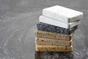 Large selection of stone samples for countertops and floors. Pieces of artificial acrylic stone in a sample box. A set of shades of countertops of different textures