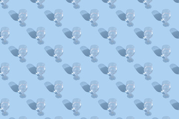 Glasses with water and shadow pattern on blue background