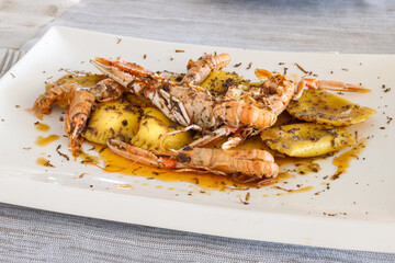 Ravioli stuffed with ricotta and truffle, sautéed with butter, sage and scampi