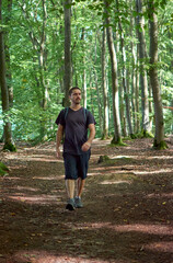 A Hispanic man with a backpack walking in the forest