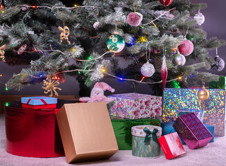 Naklejka na ściany i meble Boxes of presents under decorated artificial Christmas tree.